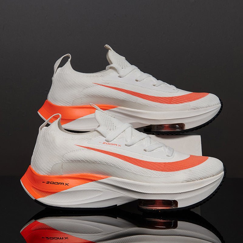 White and orange sneakers with 'zoom x' text on a reflective black surface