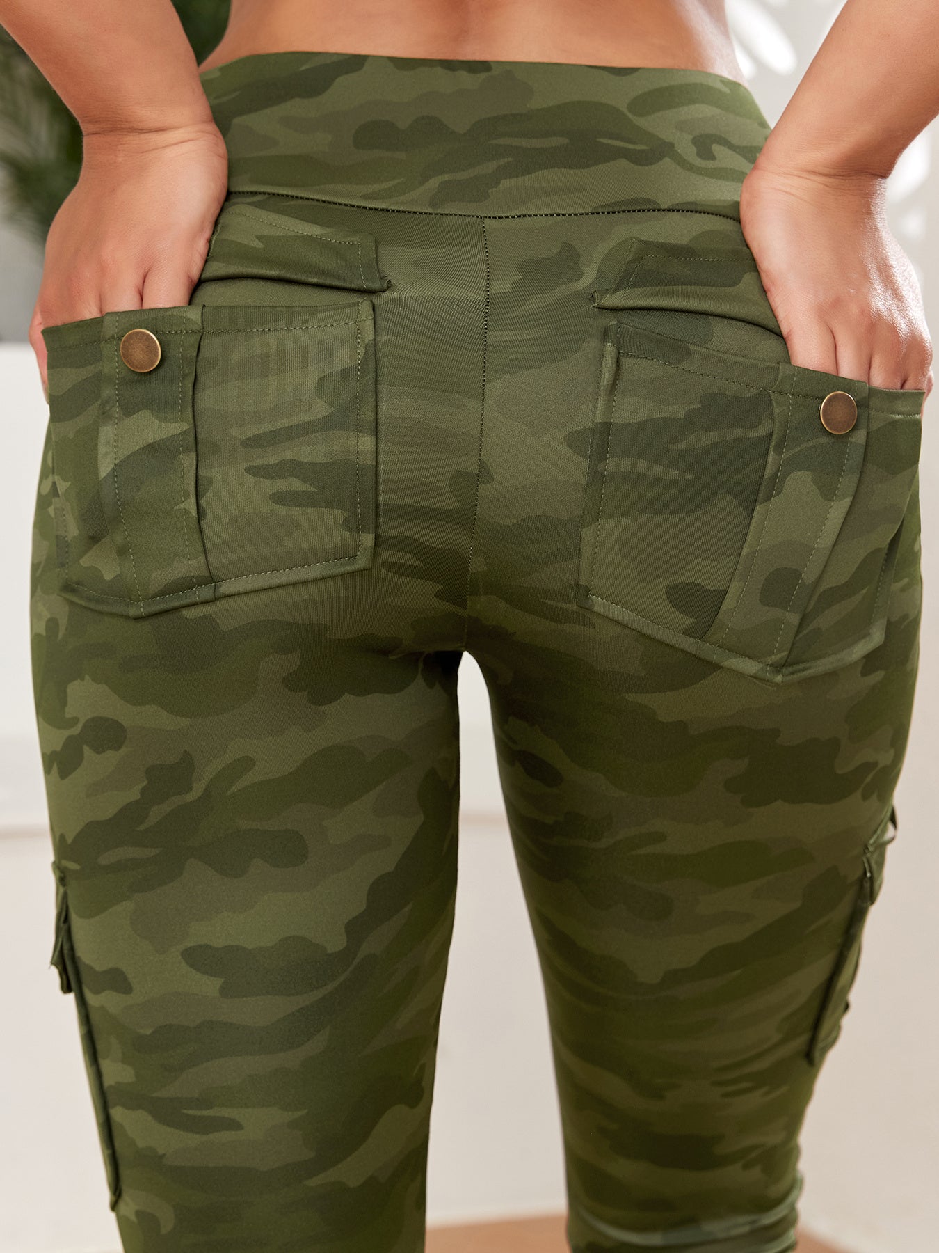 Green camouflage pants with pockets on a neutral background