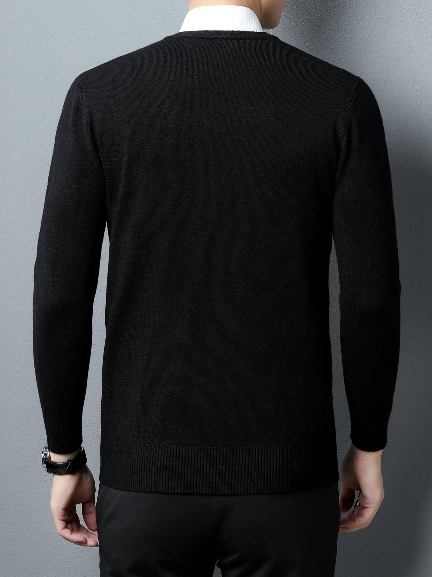 Person wearing a black Men's Knitted V-neck Sweater against a gray background