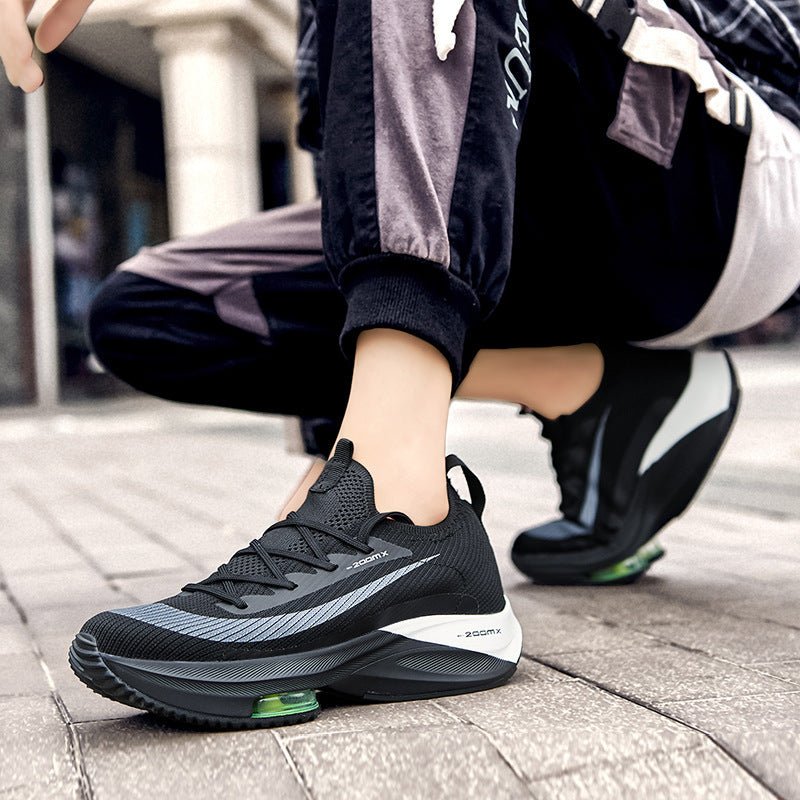 Person wearing black athletic shoes with green sole on a pavement.