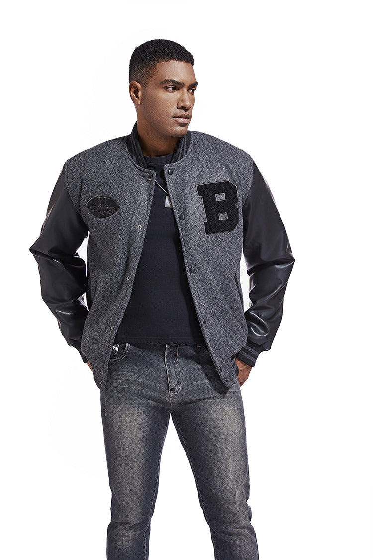 Man wearing a gray varsity American Baseball Jacket with a letter 'B' patch, black shirt, and jeans on a white background
