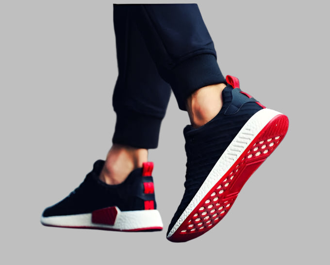 Black and red sneakers with white soles worn by a person on a gray background