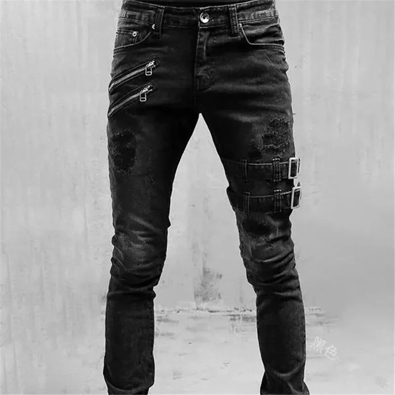 Black distressed jeans with zippers and buckles on a gray background
