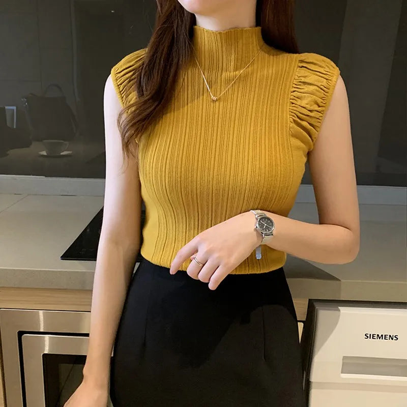 Person wearing a yellow sleeveless top and black skirt in a kitchen setting