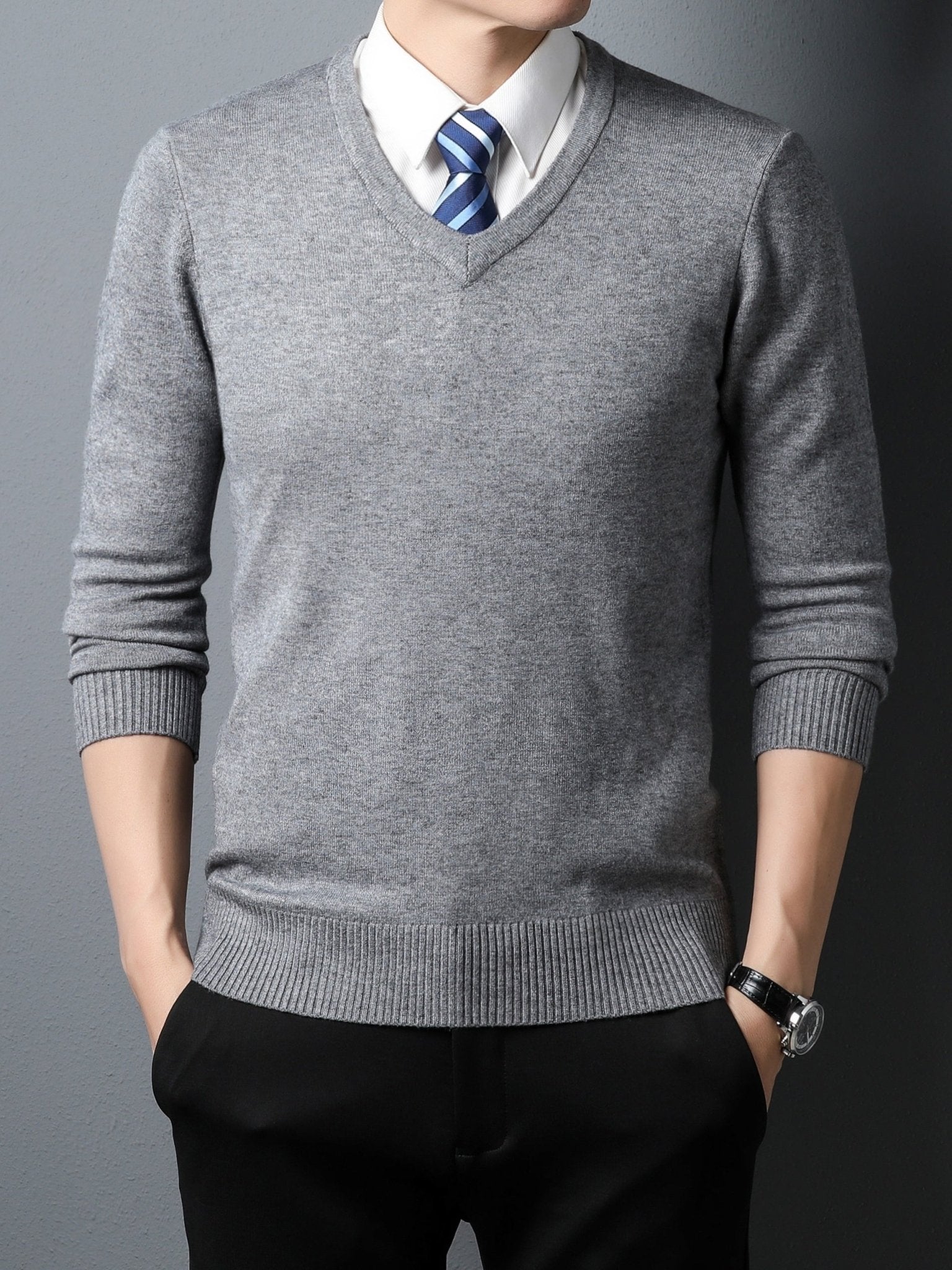 Man wearing a gray Men's Knitted V-neck Sweater a white shirt with a blue tie against a dark background